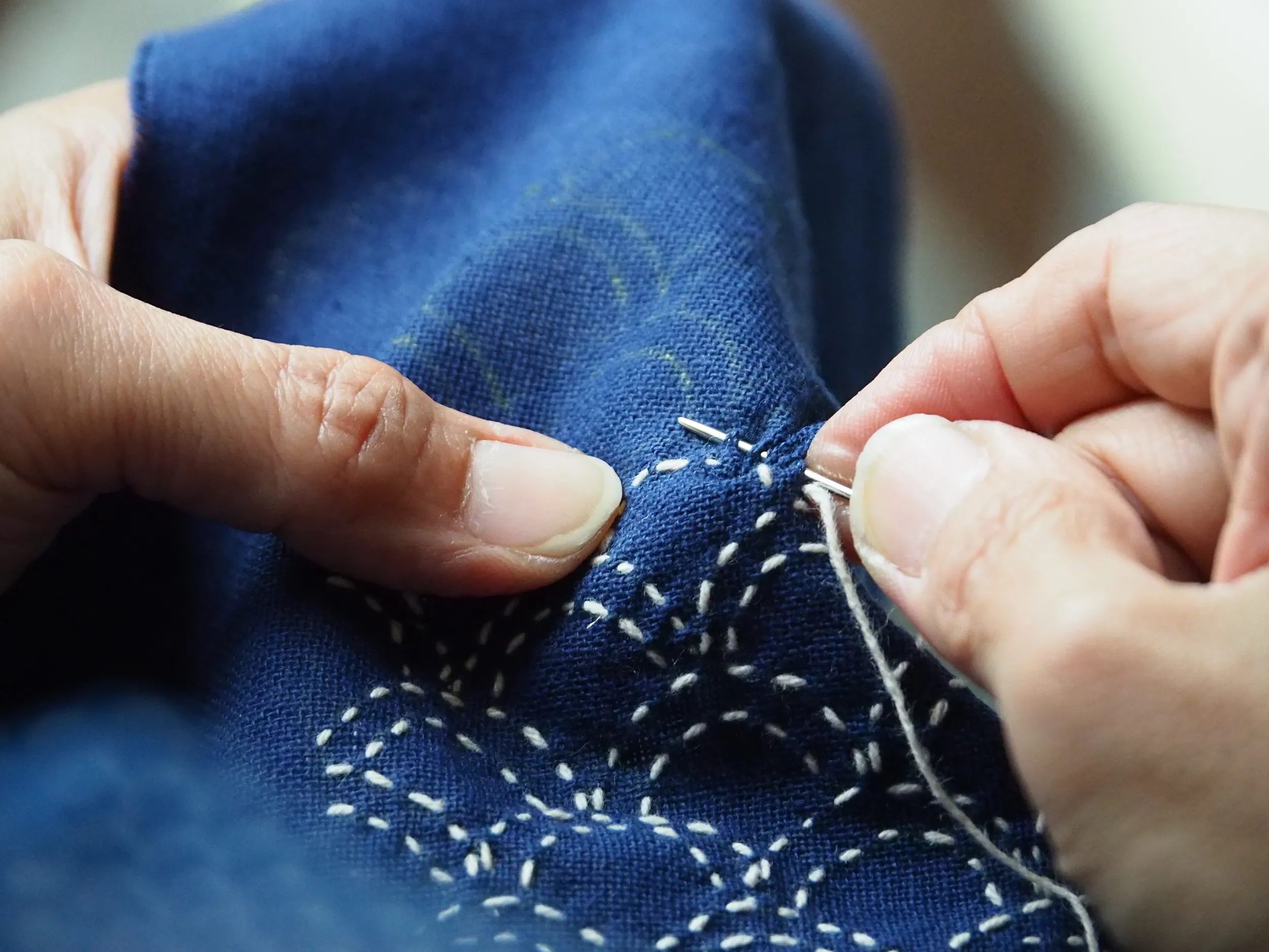 Une femme est en train de broder au sashiko