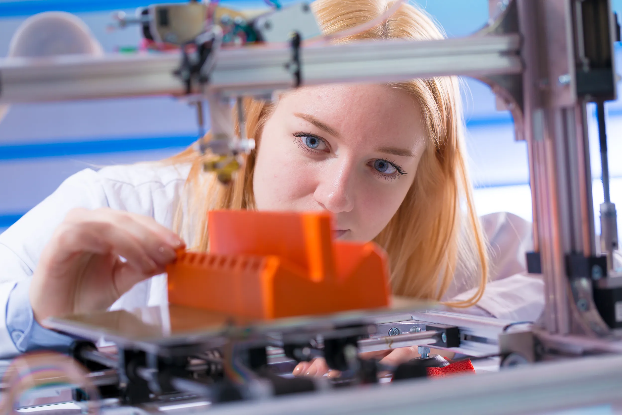 Une femme observe une imprimante 3D